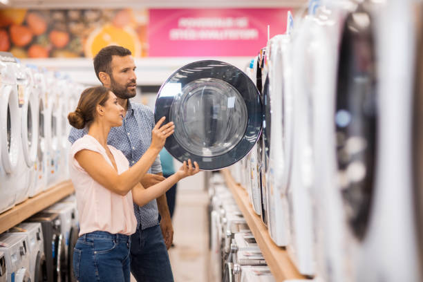 Young couple seen in a home appliances store in front of a drying machine.